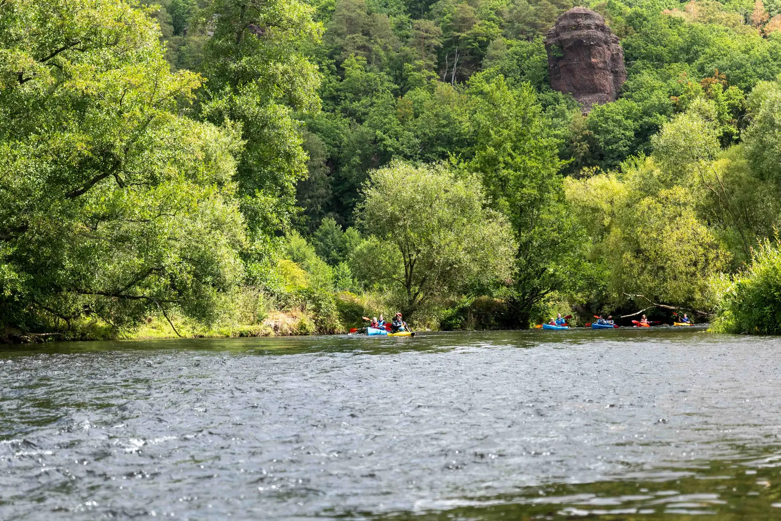 Roter Buntsandsteinfelsen über dem Rurtal, kleine Kajaks auf dem Fluss