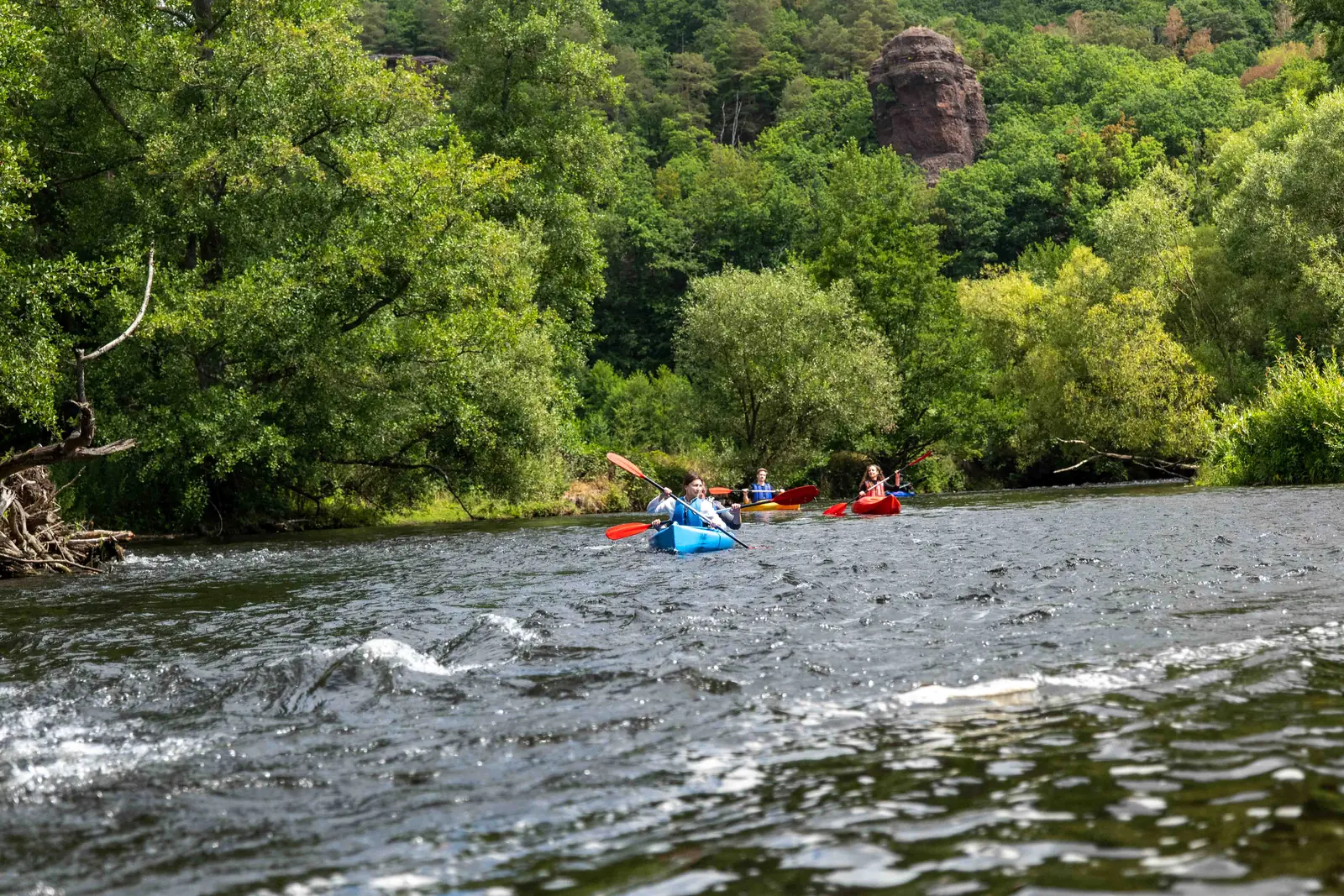 Familie im Doppelkajak auf der Rur vor den roten Buntsandsteinfelsen